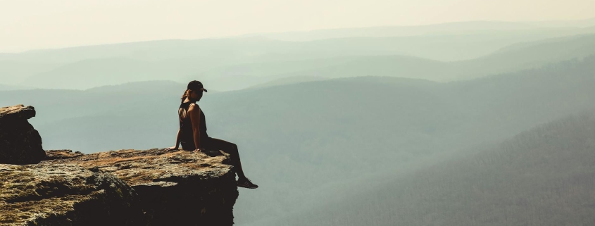 woman sitting on edge of rock formation